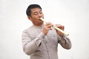 Asian flutist, musician is playing a flute, Thai musical instrument. Concept, music blowing with mouth, control with fingers on holes of flute for melody and rhythm. photo