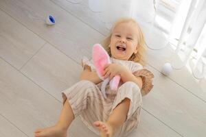 Child lying on floor with bunny ears and colorful eggs during a playful holiday celebration photo