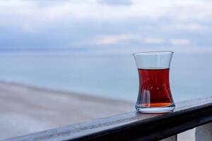 Tea glass on balcony overlooking ocean during cloudy early morning photo