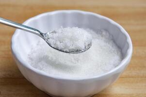 Side view of a spoon filled with coarse salt with customizable space for text or ideas. photo
