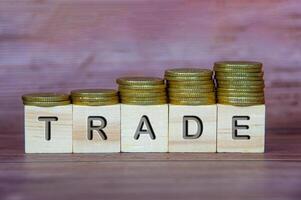 Trade text on wooden cubes with stacking golden coins. Business concept photo