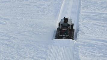 Priiskovy, Russia - January 05, 2024. Snowcat smoothing ski slopes ensuring ideal conditions aerial view Snowcat merging machinery with snowy landscapes. Snowcat's role vital in ski resort video