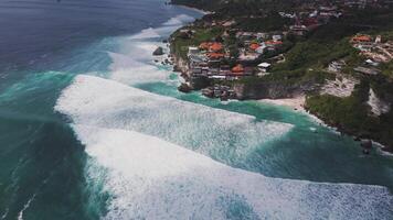 Ocean waves rolling onto a secluded beach beneath Bali's cliffs video