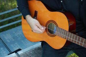 Man Tunes Guitar With Tuning Fork Outside in park photo