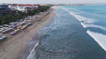 Aerial view of Kuta Beach with sunbathers, surfers, and ocean waves video