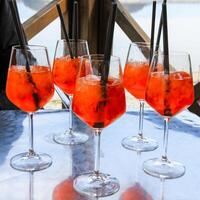 Aperol Spritz glasses with ice and straws on an outdoor table. photo