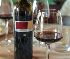 Glass of red wine with bottle on elegant dining table. photo