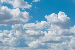 White fluffy clouds scattered across a vibrant blue sky, creating a serene and peaceful atmosphere. The clouds appear soft and majestic, adding depth to the sky's texture photo