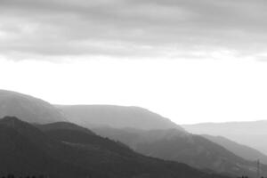 Black and white landscape of the mountain range with partly cloudy sky photo