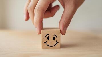 Hand placing happy face wooden block simple joy positive vibes warm tones light background photo
