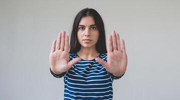 Young woman showing stop hand gesture serious expression neutral background simple studio shot clear photo