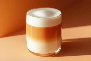 An espresso drink in a glass with a white and orange foam photo