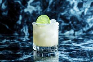 A margarita with lime and ice on a marble counter photo