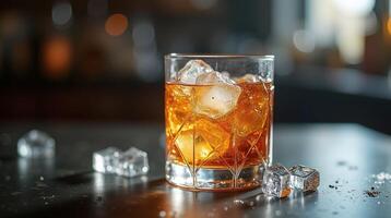 Golden beverage in a glass with ice, on a table in a dimly lit setting. photo