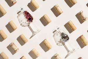 Wine corks and Christmas decoration as wine glass on beige background with hard light, shadows at sunlight. Creative minimal pattern, sparkling new year background, holiday drink concept photo