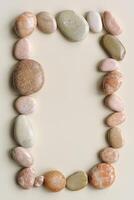 Top view frame with close up round pebbles sea stones on sand color background. Square composition from natural stone. Minimal style framing, summer concept, empty space for text, vertical photo