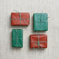 Holiday handmade gift boxes, square geometric pattern on linen cloth background, green, red paper-wrapped presents with rough thread, minimal aesthetic flat lay gifts simple present handmade photo