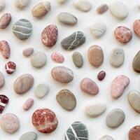 Background with natural colored sea stones. Smooth round pebbles as pattern on light background. Minimal summer card, still life with various grey, pink rocks, spa and relaxation concept photo