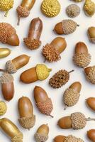 Acorn painted gold color isolated on beige background. Autumn time concept. Fall harvest season, autumnal natural materials, pattern from acorns. Trend nature flat lay, aesthetic fall, vertical photo