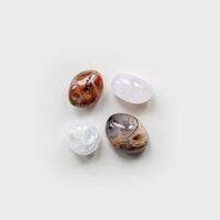 Top view close up pebbles stones on white light background. Square composition from natural gemstones sardonyx and quartz. Minimal style flat lay, design object. Creative summer pattern. photo