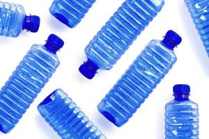 Pattern from Clear plastic water bottles with blue cap on white background with soft shadow, Minimal top view, themes of ecology, recycling, sustainable living, reduce disposable plastics concept photo