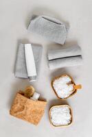 Spa, wellness, bath products as minimal aesthetic pattern, magnesium salt flakes, folded grey towels, natural brushes, massagers, reusable pads, gray background, top view lifestyle content, photo