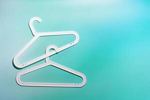 Top view White Plastic hangers, minimal style layout on white teal gradient background, Clothes rack for organizing clothes in closets or retail stores, fashion, organization concept, copyspace photo