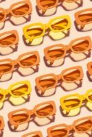 Pattern of Trendy sunglasses with Yellow orange Frame on peach background, beach vibes, summertime mood, sunlight shadow, Summer vacation, summer rest concept. Minimal style layout of eyeglasses photo