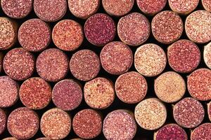 Wine cork background from red wine, natural texture used bottle stoppers top view. Closeup wooden red stain corks. Natural textured stoppers colored wallpaper. Bright background wine corks photo