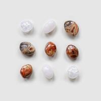 Creative arrangement of natural colored stones. Smooth round pebbles as square pattern on light white background. Minimal summer flat lay, top view composition with different gemstones photo