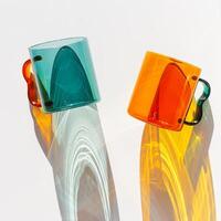 Two Modern Glass Cups with Vibrant sunlight Shadows, Aesthetic Top view of transparent orange and teal color glass mugs for drink. Yellow green reflections, shadow on white, minimal lifestyle design, photo