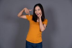 Smiling Portrait of a Young Female Pointing Down with Joyful Expression photo