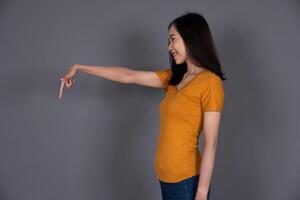 Smiling Portrait of a Young Girl Pointing Down with Joyful Expression Isolated Background photo