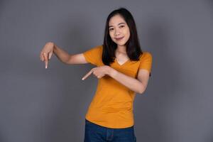 Smiling Portrait of a Young Woman Pointing Down with Joyful Expression photo