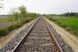 Railway tracks through green crop fields photo