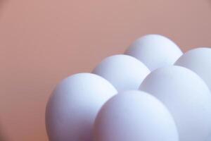 White Eggs arranged against Soft Pink backdrop, creating minimalist and modern aesthetic. Smooth, round shapes and pastel tones offer serene visual appeal, ideal photo for contemporary design themes