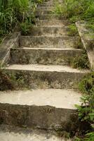 Close up of stone stairs with interesting texture and solid natural stone walls covered with some moss photo