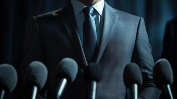 The politicians striking charcoal grey suit contrasts sharply with the bright welllit backdrop of a press conference highlighting the sharp lines of the tailored jacket. Their eye photo