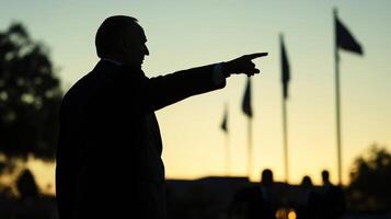 Clad in a tailored suit a politician points toward a nearby feature in the plaza passionately explaining a community initiative. The blurred silhouettes of curious onlookers and flagpole photo