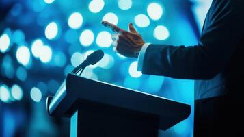 Captured in midsentence a politician deftly emphasizes a point with a raised hand at a polished podium. The outoffocus blue hues in the background create a serene yet impactful settin photo