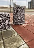 Urban concrete block situated on a red brick pavement and textured stone trash bin The scene captures modern architectural development photo