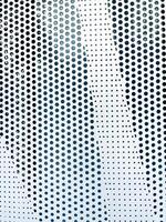 Perforated metal panel forms geometric pattern with circular holes creating distinctive design. The varying sizes and arrangement of holes abstract background, copy space photo