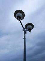 minimalist photo of modern street lamp with two globe-shaped lights, set against an overcast sky, emphasizes the simplicity and functionality of urban design