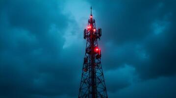 A cell tower with red lights on it in front of a dark sky photo