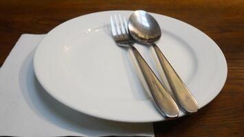 A clean white plate and silverware are placed on the table, beautifully lit by soft lighting photo