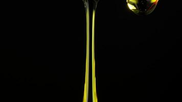 Thick yellow liquid infused with glitter slowly dripping against a black background. The close-up captures the viscous flow and the sparkling particles as they descend. video