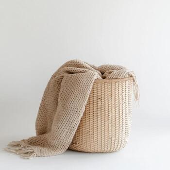 Woven laundry basket with soft throw blanket arranged neatly for organization in a minimalist setting photo