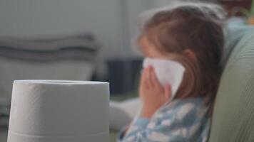 Sick girl sneezing into tissue at home focus on foreground video