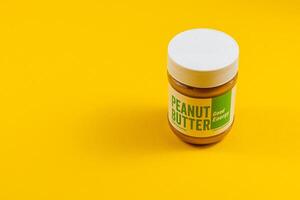 Lviv Ukraine 04.02.25 Peanut butter jar on vibrant yellow background photo