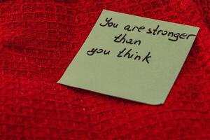 Message of encouragement on a note placed on a red textured surface photo
